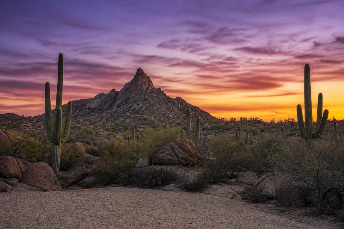 Granite summit spire of Pinnacle Peak at dusk with saguaro silhouettes on the darkening slope below