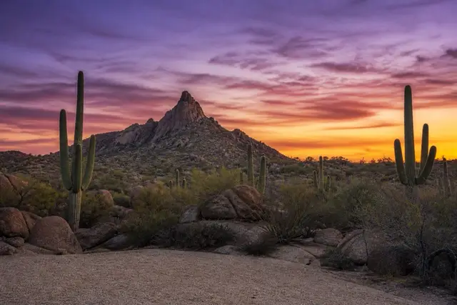 Granite summit spire of Pinnacle Peak at dusk with saguaro silhouettes on the darkening slope below